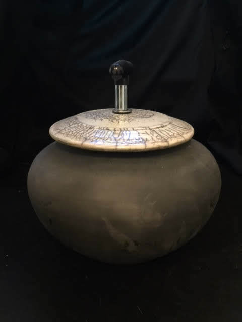 black raku fire pot with white lid and wood handle